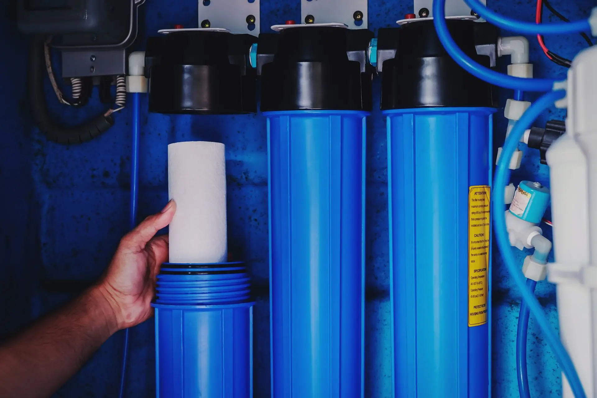 Technician replacing a cartridge in blue filter housings