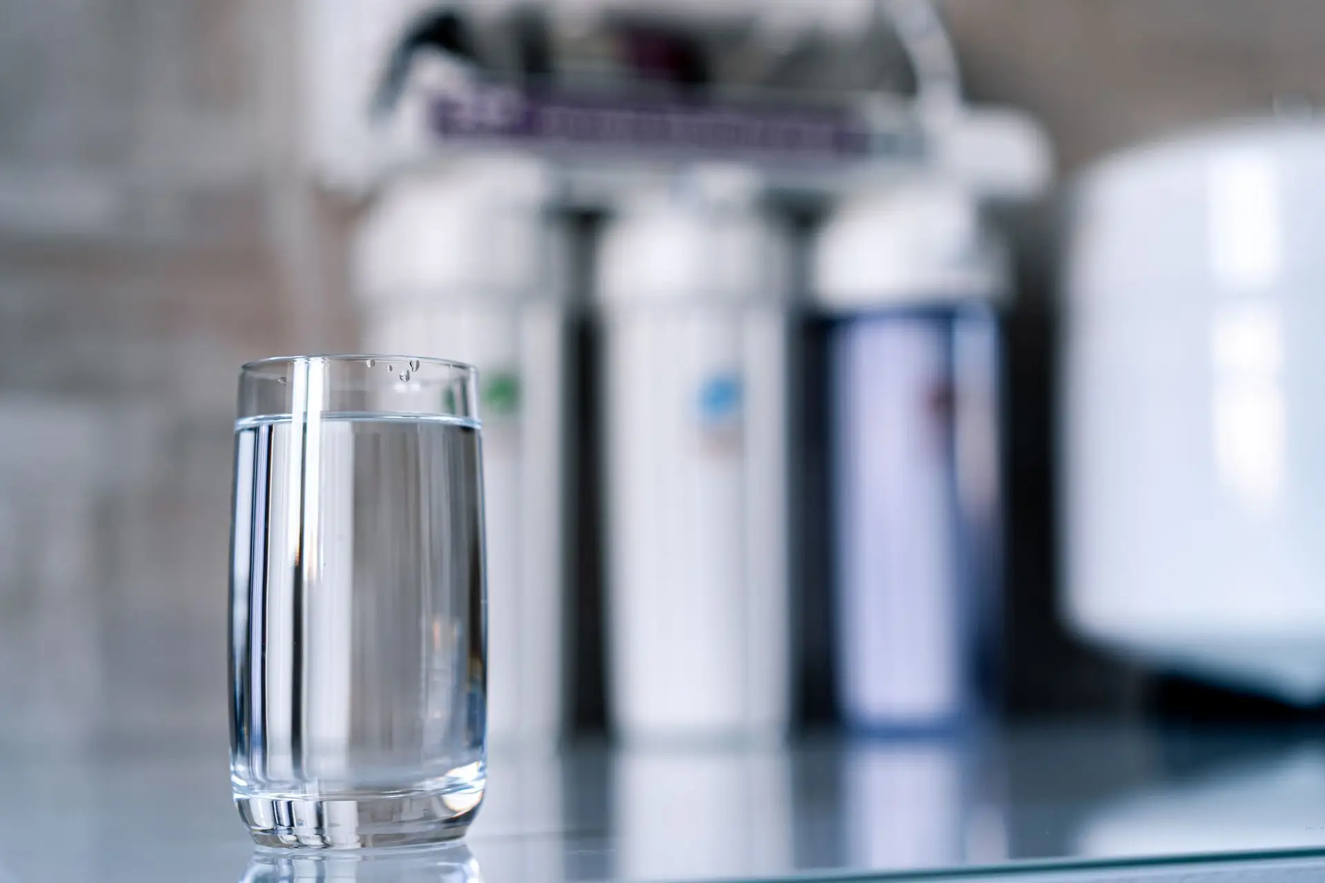 Glass of filtered water in front of a filtration system